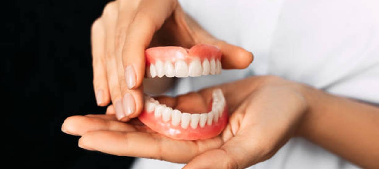 Close up of hands holding dentures